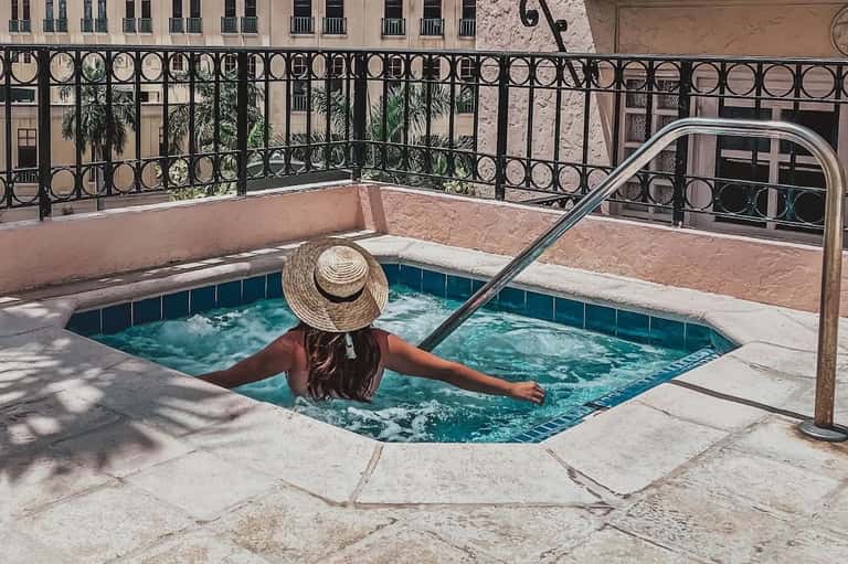 Person relaxing in small decorative pool with ornate black railing and historic building
