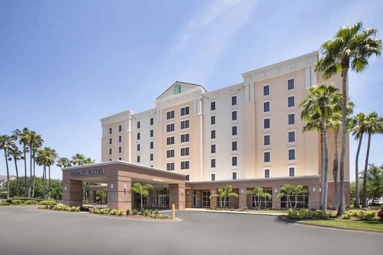 Embassy Suites hotel exterior with cream-colored building, palm trees, and entrance awning