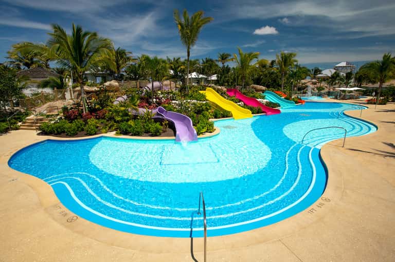 Resort water park with bright colored slides, winding lazy river, and palm trees