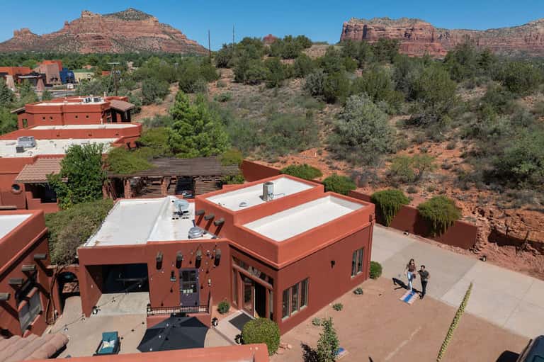 Red-earth architecture resort nestled in desert landscape with red rock formations and desert vegetation