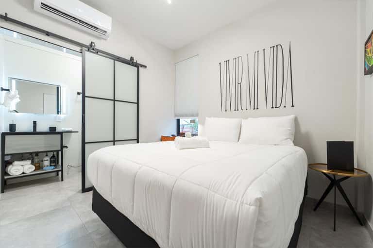Contemporary hotel bedroom with white bedding, ensuite bathroom, and minimalist decor