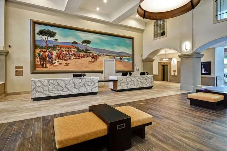 Spacious hotel lobby with dual reception desks, high ceilings, and large landscape artwork