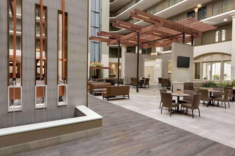 Modern hotel lobby with wooden pergola, neutral furniture, and stone accent walls