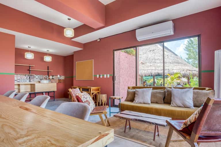Modern lounge with coral walls, wooden furniture, fireplace, and large windows overlooking beach bungalows