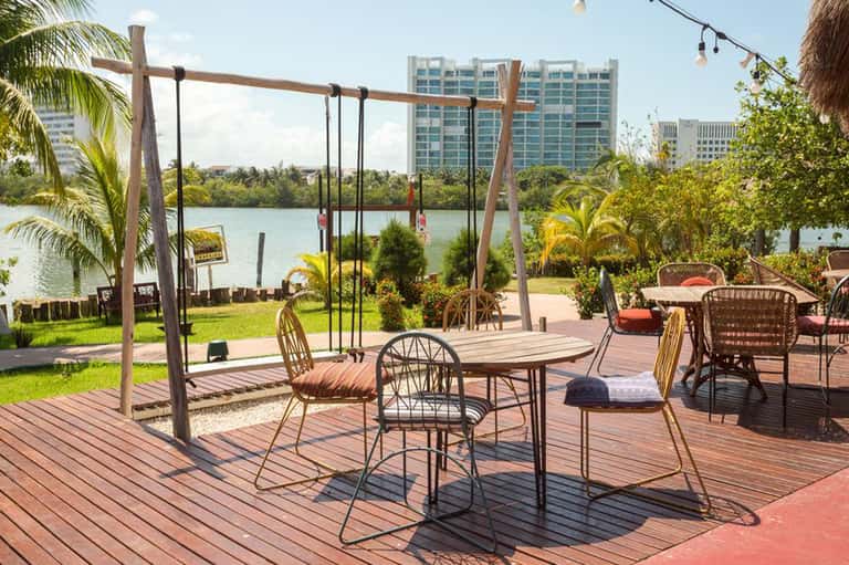 Waterfront patio with swings, dining table, and view of high-rise buildings across lake
