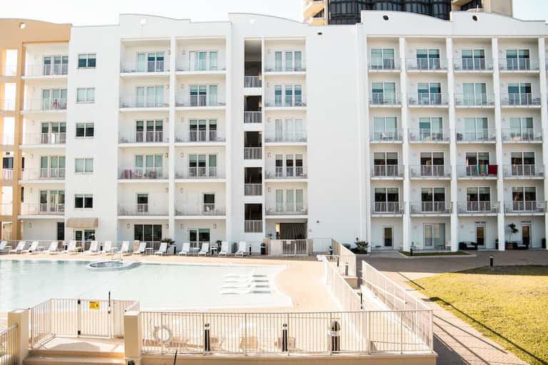 Modern white beachfront resort building with pool and sandy beach access