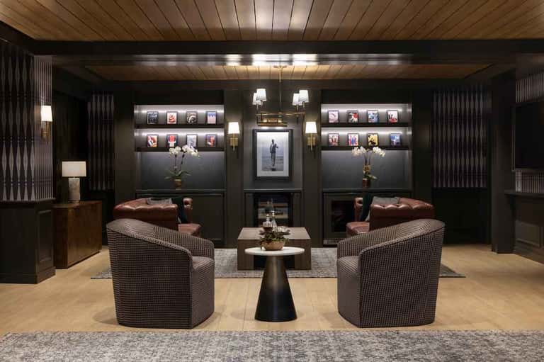 Luxury lounge with dark walls, illuminated artwork, leather seating, fireplace, and modern decor