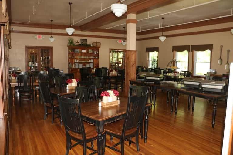 Elegant dining room with wooden beams, dark furniture, and large windows with flower centerpieces