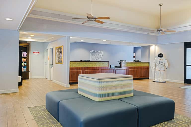 Hotel lobby interior with welcome desk, blue seating, and decorative astronaut figure