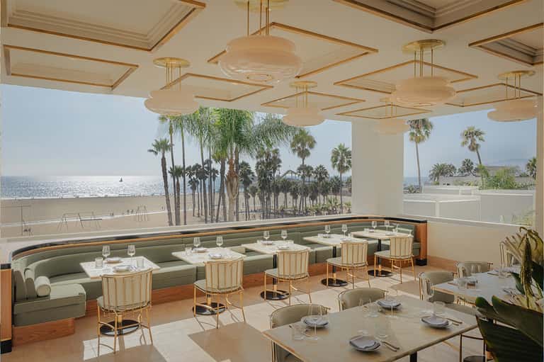 Upscale beachfront restaurant with green banquette seating, pendant lights, ocean view, palm trees