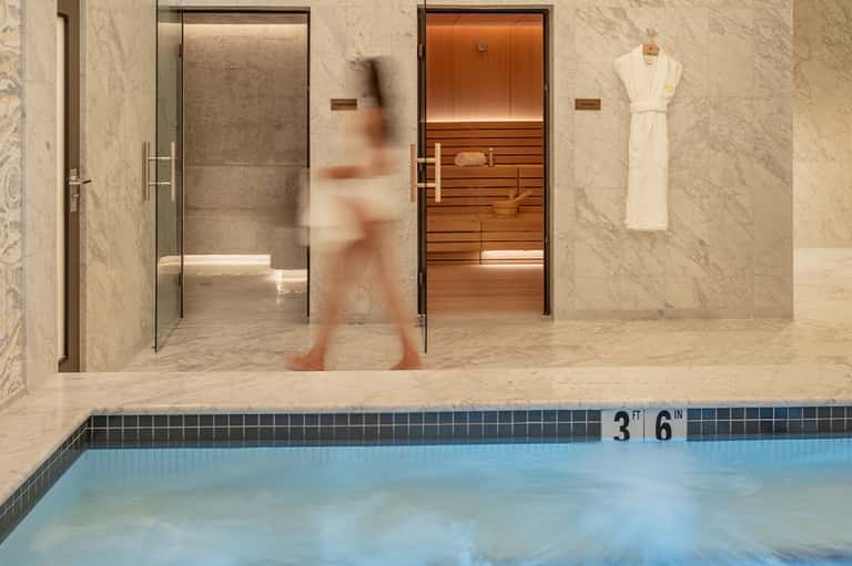 Spa area with steam sauna, shower stall, and swimming pool at hotel wellness center
