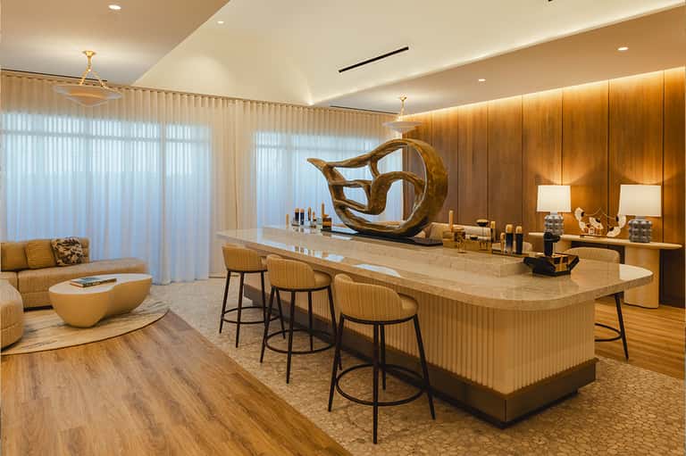 Modern spa reception area with wooden accents, marble counter, artistic bronze sculpture, and ambient lighting