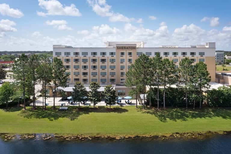 Sheraton hotel exterior with white and tan facade surrounded by pine trees and waterfront grounds