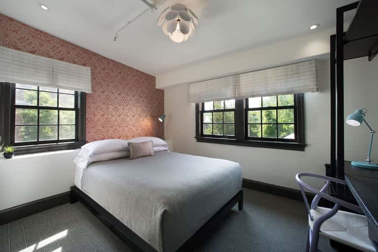 Modern hotel bedroom with queen bed, patterned accent wall, and large windows