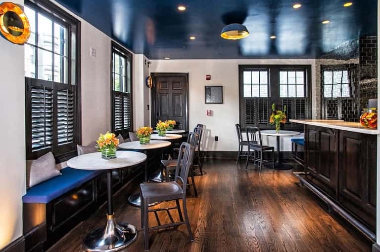 Contemporary restaurant interior with dark wood accents, gold pendant lights, and booth seating