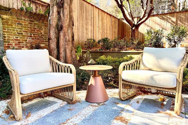 Two woven rattan lounge chairs with white cushions in backyard seating area