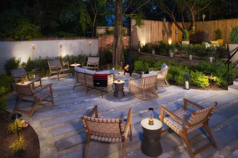 Backyard entertaining space with fire pit, lounge seating, and ambient landscape lighting