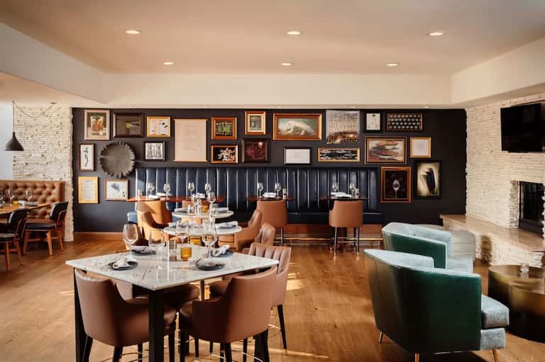 Elegant dining room with dark feature wall, gallery art, banquette seating, and fireplace