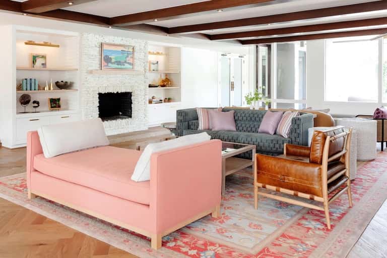 Contemporary living room with pink sofa, fireplace, built-in shelving, and natural light