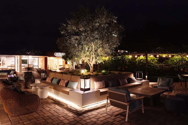 Nighttime outdoor lounge area with illuminated seating, trees, and ambient lighting