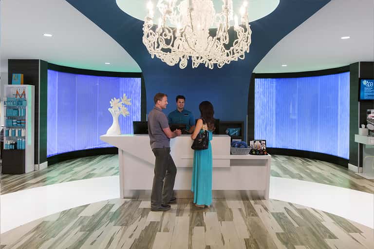Contemporary hotel lobby with teal accent walls, white reception desk, and crystal chandelier