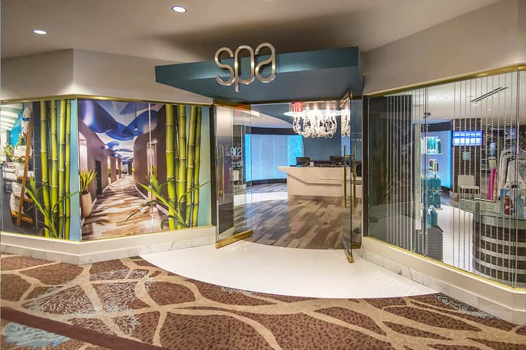 Modern spa entrance with teal accent wall, brass lettering sign, and contemporary interior design