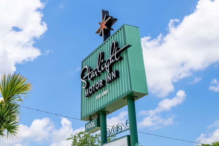 Vintage-style green neon sign reading Starlite Motor Inn with pool indicator