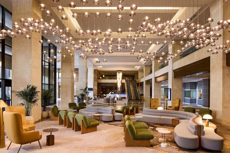 Luxurious hotel lobby with copper pendant lights, marble columns, and contemporary seating