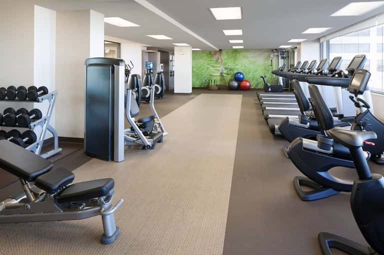 Fitness center with cardio equipment, dumbbells, and green accent wall