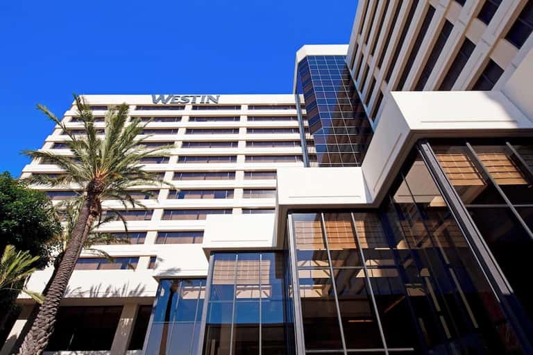 Westin hotel exterior with white facade, palm tree, and glass entrance doors