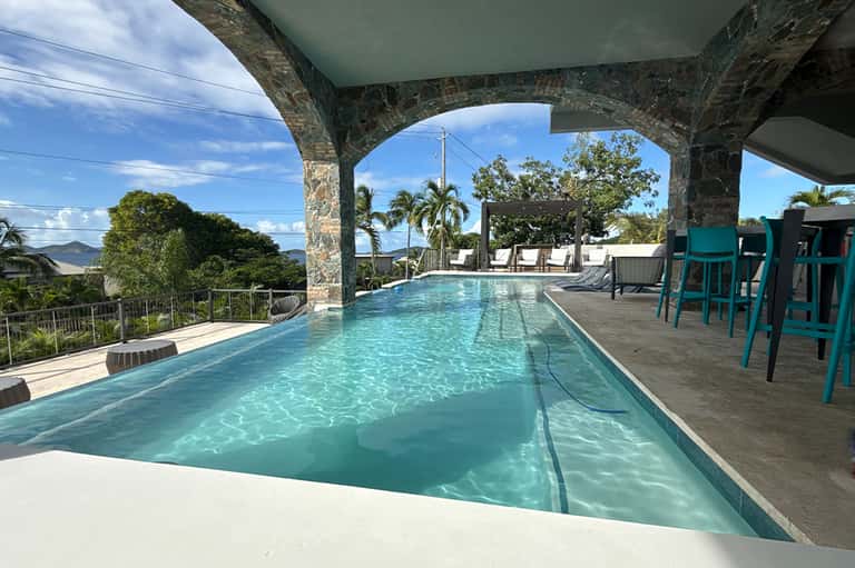 Lap pool under covered structure with mountain and tropical landscape views