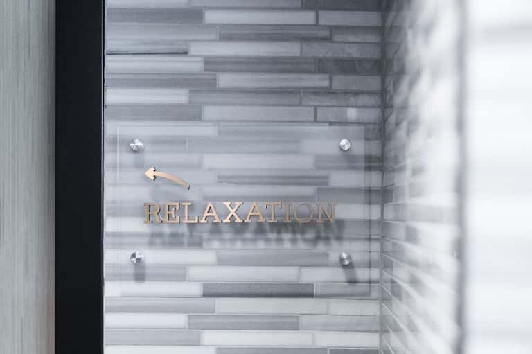 Glass door entrance to relaxation spa area with tile flooring and bronze lettering