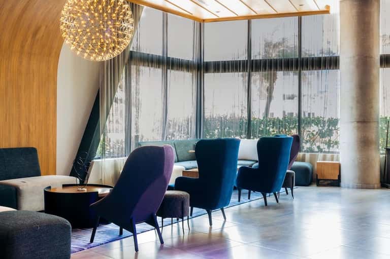Modern hotel lobby lounge with blue velvet chairs and floor-to-ceiling windows