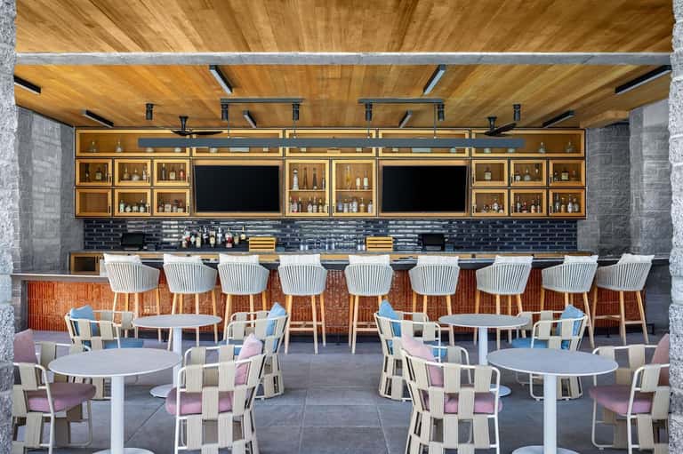 Contemporary bar and lounge area with wooden ceiling, bar seating, and dining tables