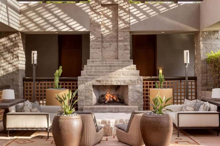 Outdoor courtyard with central fireplace, lounge seating, and pergola shade structure
