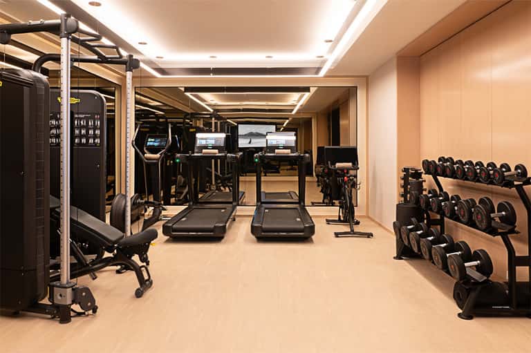 Fully-equipped fitness center with treadmills, stationary bikes, dumbbells, and mirrors