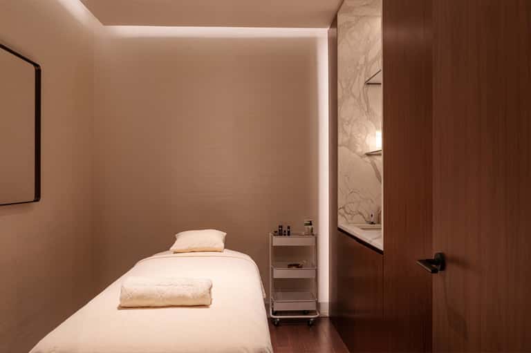 Minimalist spa treatment room with massage bed, ambient lighting, and marble accents