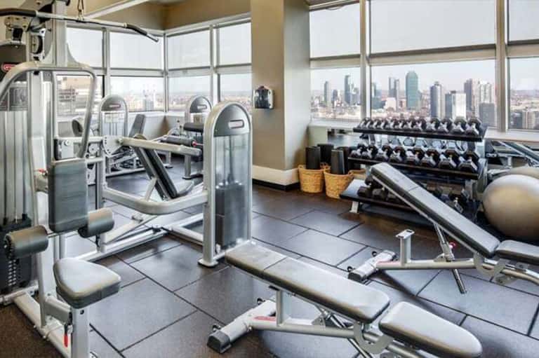 Modern high-rise fitness center with city skyline views through floor-to-ceiling windows