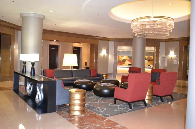Upscale hotel lobby with red accent chairs, black furniture, and crystal chandelier