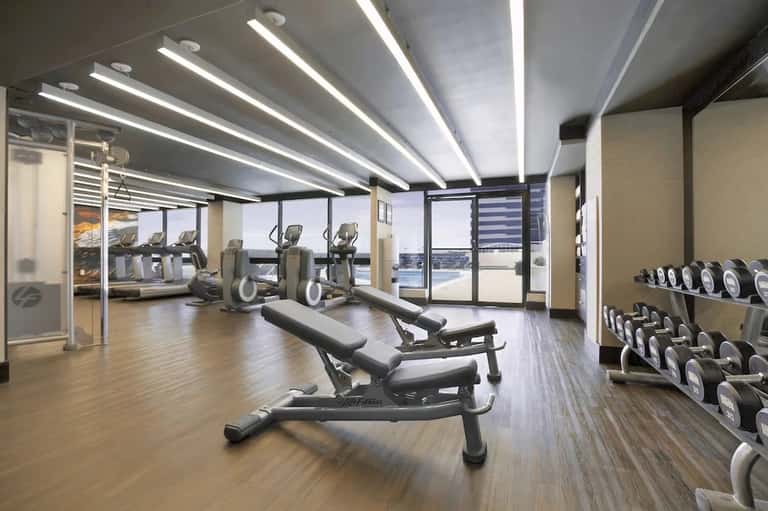 Modern hotel fitness center with cardio equipment, free weights, and floor-to-ceiling windows