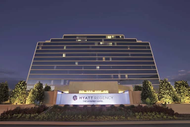 Modern hotel exterior at dusk showing illuminated geometric glass facade with Hyatt Regency signage