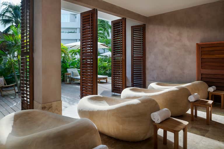 Modern spa relaxation area with curved stone loungers and open-air wooden doors