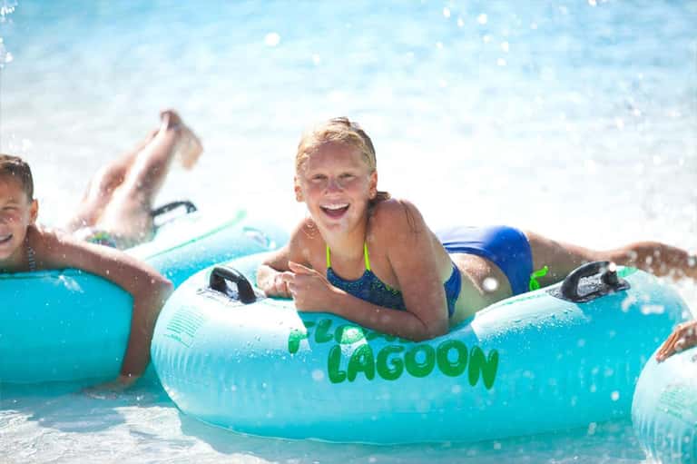 Children and adults enjoying turquoise water on inflatable Lagoon floats at beach resort