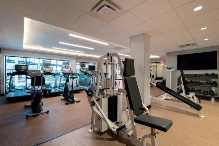 Gym with exercise equipment, weights, treadmills, and floor-to-ceiling windows with city views