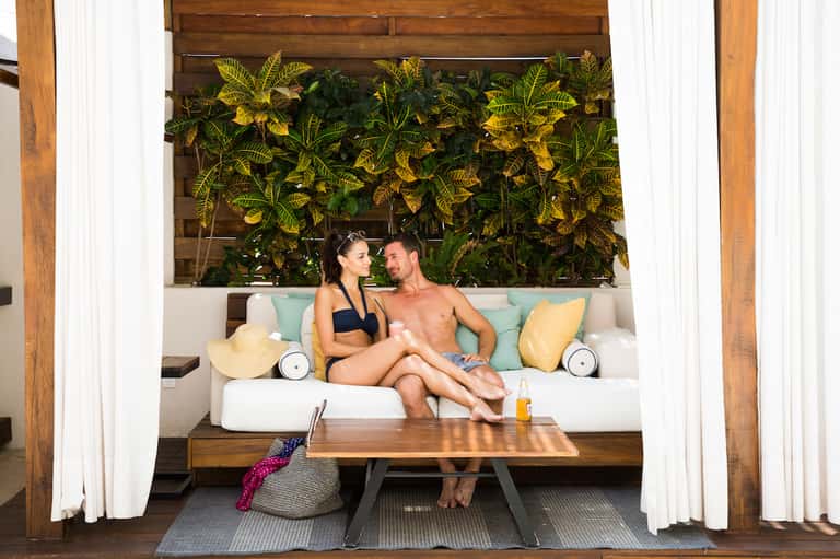 Couple relaxing on modern lounge seating with tropical plant backdrop and ocean views