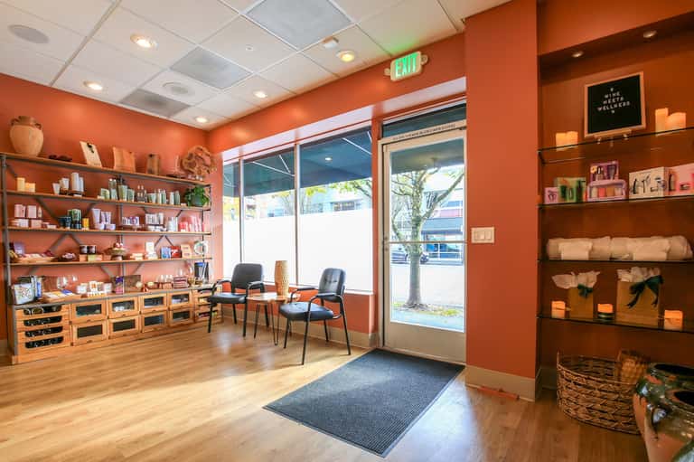 Orange wellness spa interior with shelving, products, seating, and natural light from windows