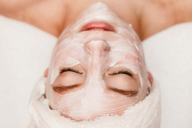 Person wearing pink face mask treatment with eyes closed for spa skincare