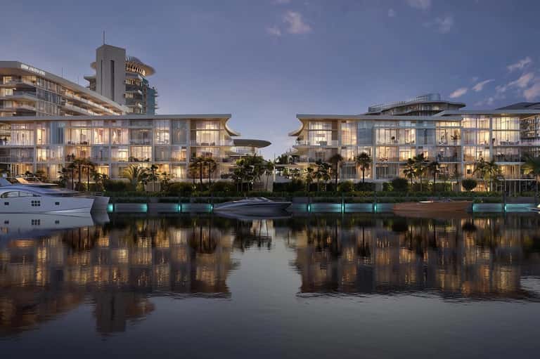 Contemporary waterfront resort buildings reflected in calm water at dusk with palm trees