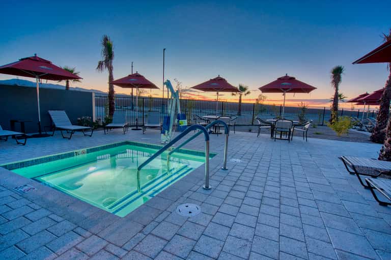 Resort hot tub at dusk with burgundy umbrellas, lounge chairs and ocean view