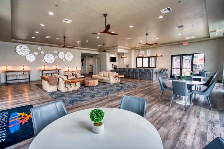Contemporary resort common area with lounge seating, dining tables, decorative plates, and bar counter